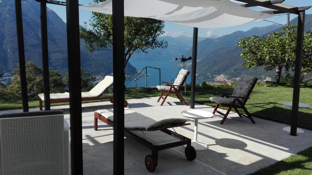 a patio with chairs and an umbrella with a view at Essentia Guest House in Faggeto Lario 