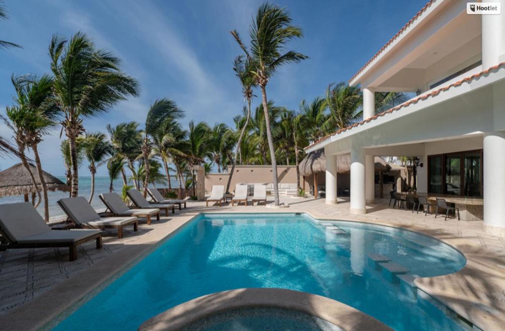 a swimming pool next to a house with palm trees at Mansion Villa in Soliman Bay for 34 guests! in Tulum