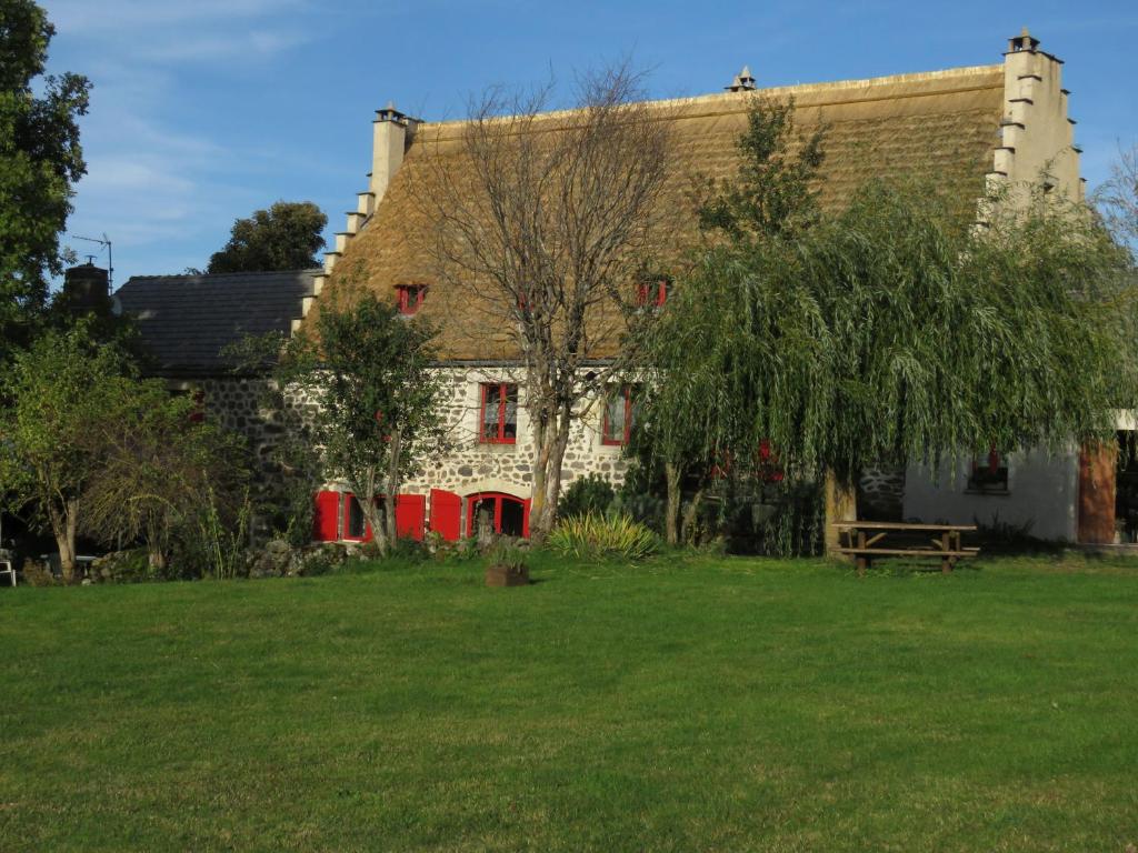 a house with red doors and a green yard at La Chaumière d'Alambre in Moudeyres