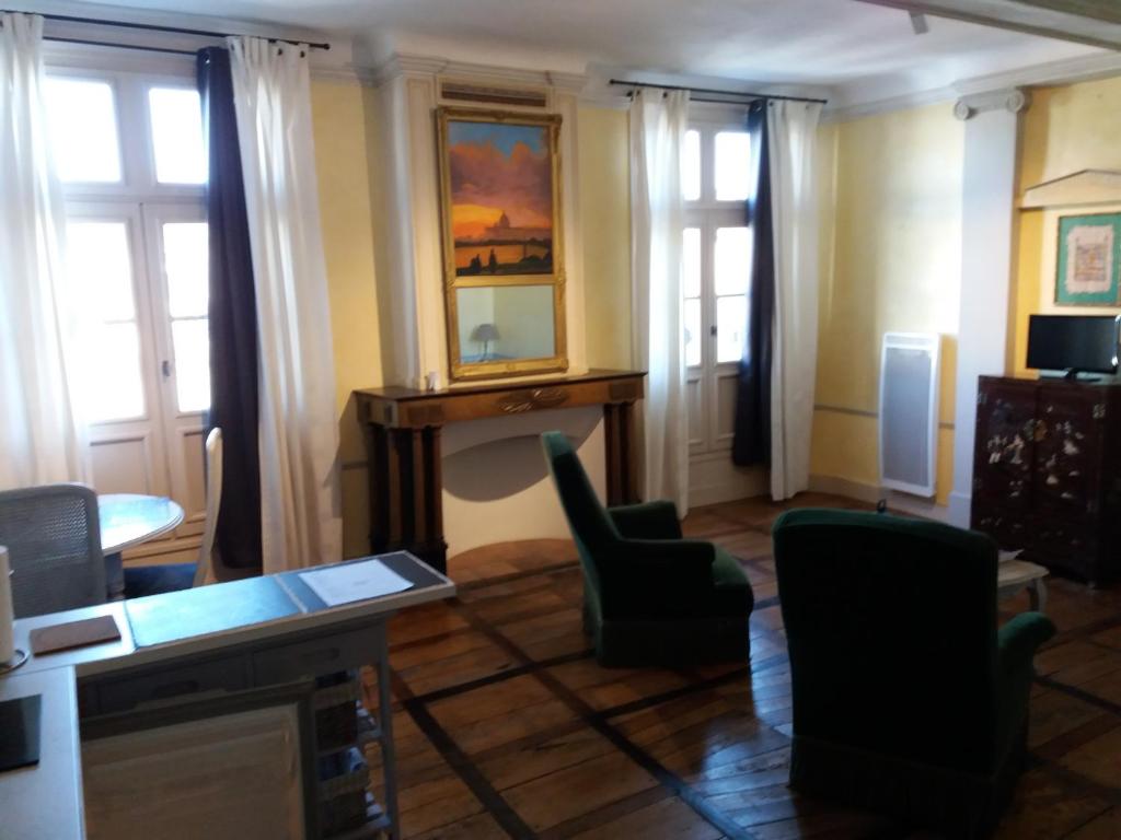 a living room with a desk and chairs and windows at Studio de Tourisme Tilleuls in Grenade-sur-lʼAdour