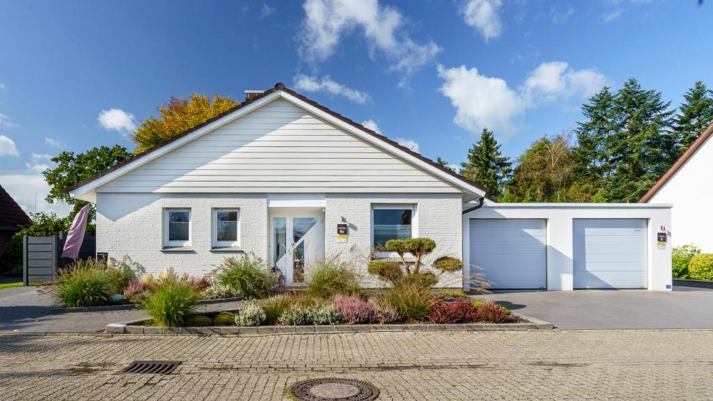 een wit huis met een garage bij Ferienappartement Ennens in Rhauderfehn