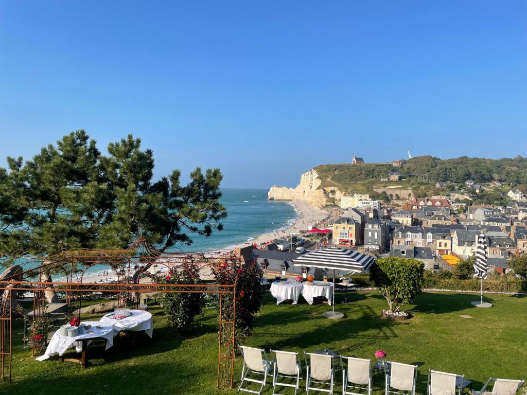 a group of tables and chairs on a lawn next to the ocean at Dormy House in Étretat