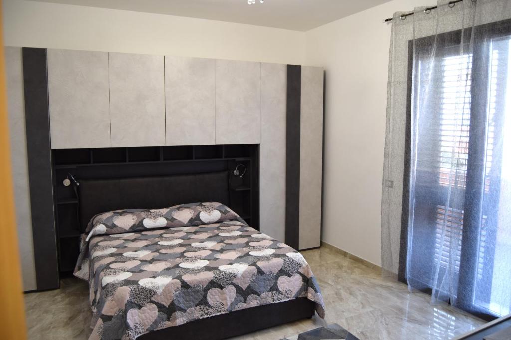 1 dormitorio con 1 cama con cabecero y ventana en Casa D'Amico, en Arnesano