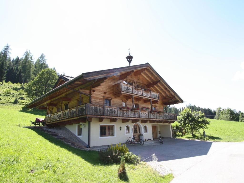 a large wooden house with a balcony on a hill at Villa on a courtyard near the ski area in Salzburg in Eben im Pongau