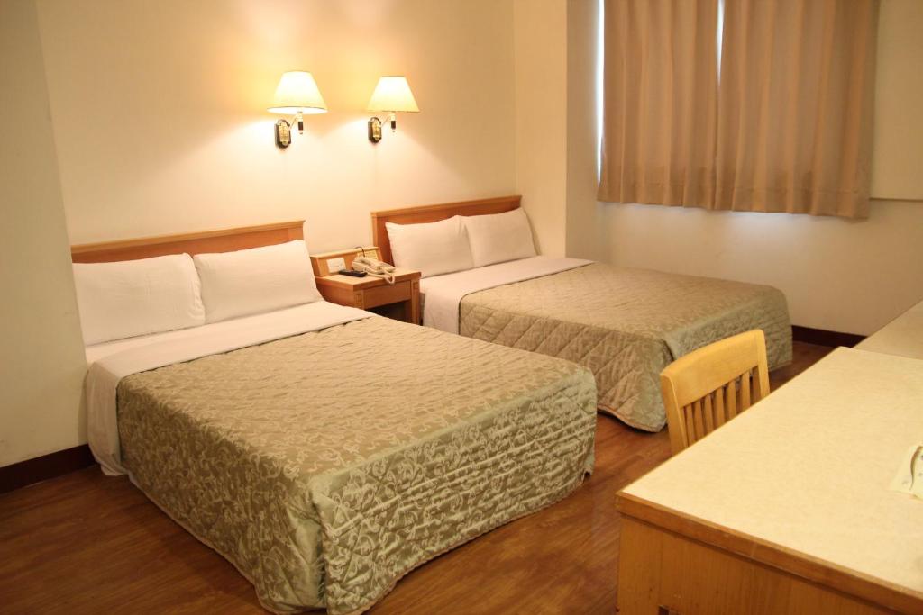 a hotel room with two beds and a table at 金馬大飯店 Riverside Hotel in Kaohsiung