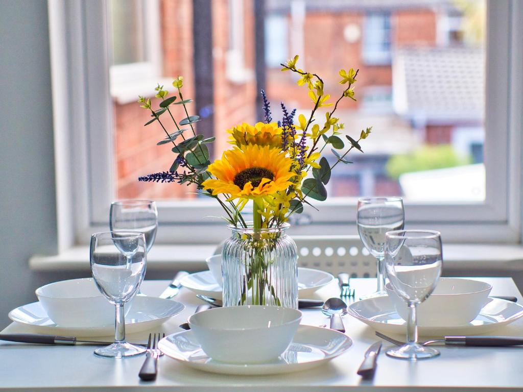 a table with a vase of sunflowers and plates and glasses at Amazing 1 bed flat in lovely area in Birmingham