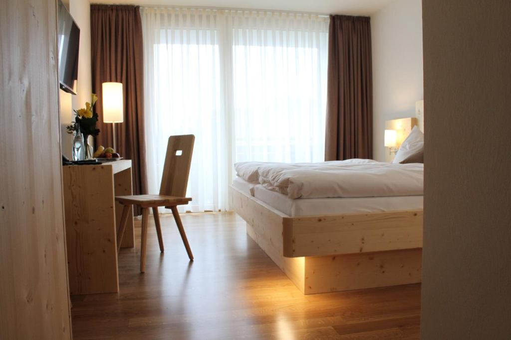 
a hotel room with a bed, chair, table and lamp at Beim Rinderwirt in Sigmaringendorf
