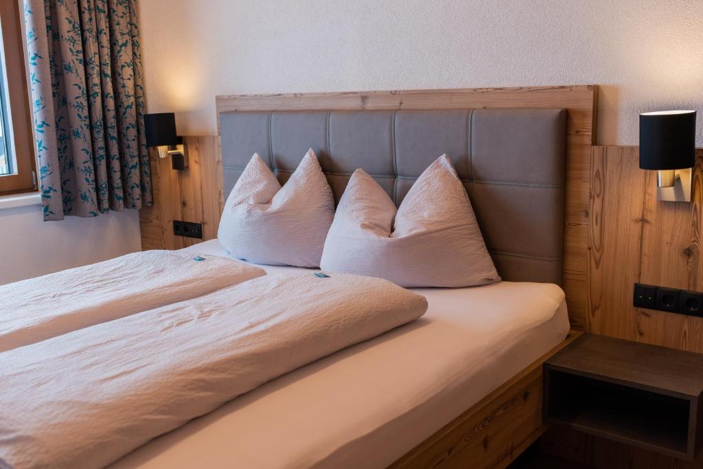 Una cama con cuatro almohadas encima. en Mountain Lodge, en Galtür