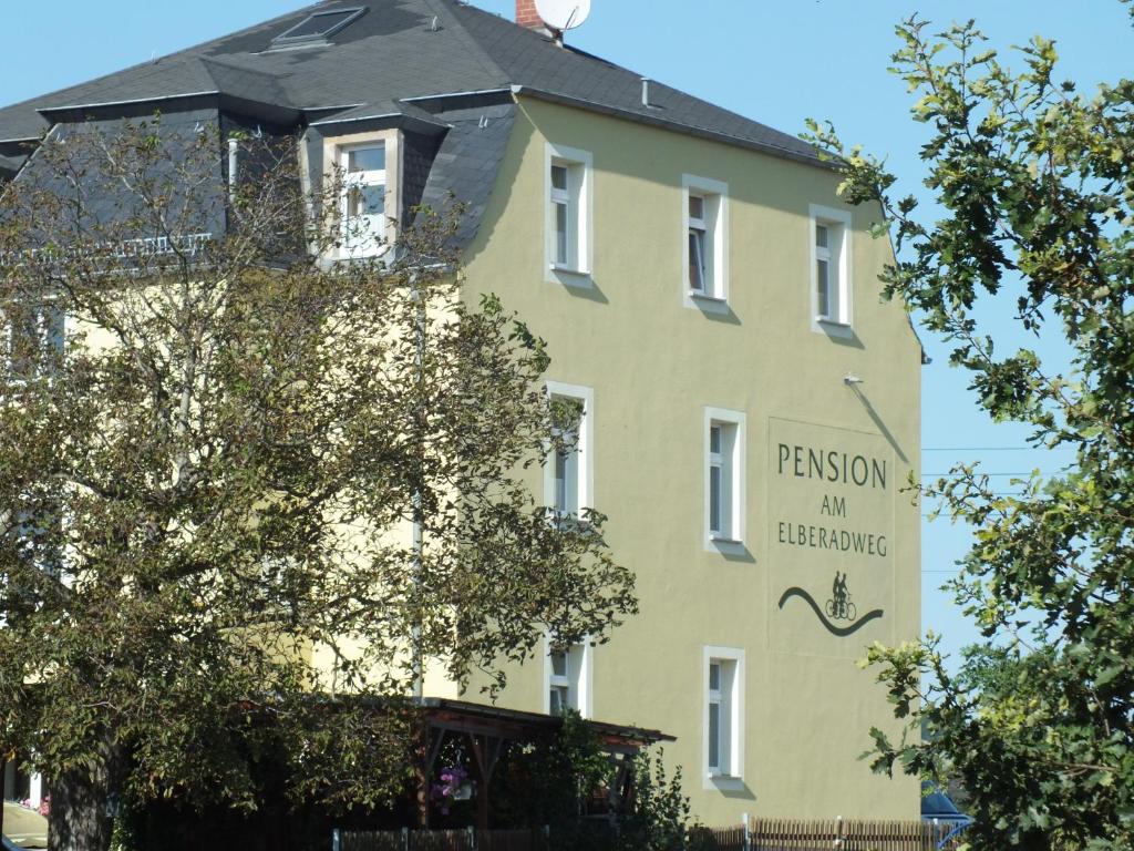 a yellow building with a sign on the side of it at Pension am Elberadweg in Radebeul