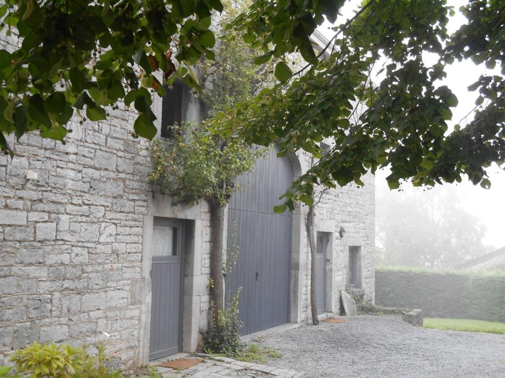 uma casa com uma porta cinzenta e um edifício de tijolos em B&B A l'Ombre du Tilleul em Aywaille