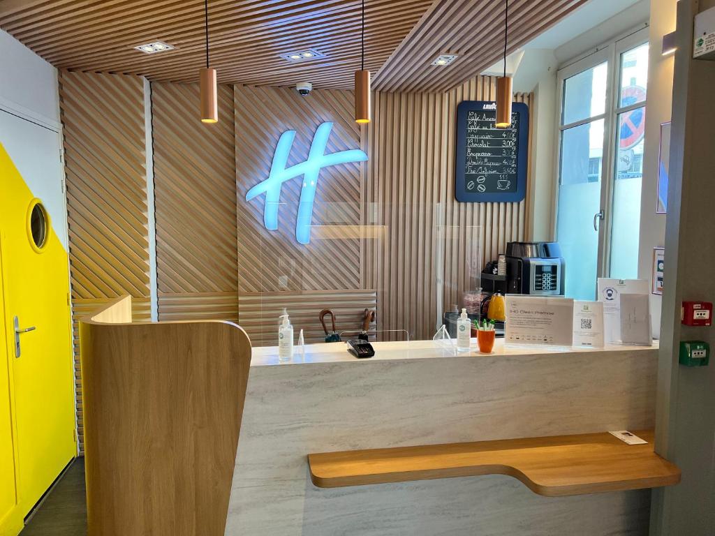 a restaurant with a counter with a sign on the wall at Holiday Inn Paris-Auteuil, an IHG Hotel in Paris