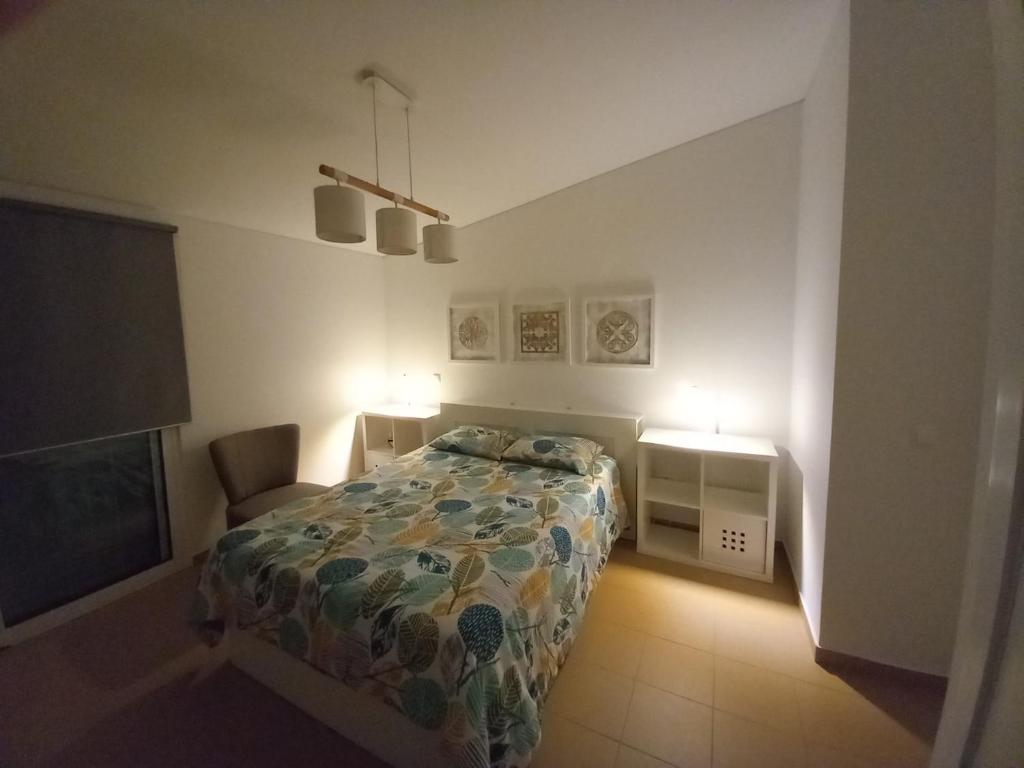 a bedroom with a bed and a chair and two lights at Charming Beach Villa Porto Santo in Porto Santo