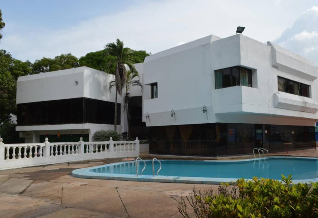a building with a swimming pool in front of a building at Habitaciones Familiares Hacienda Botero in Turbaco
