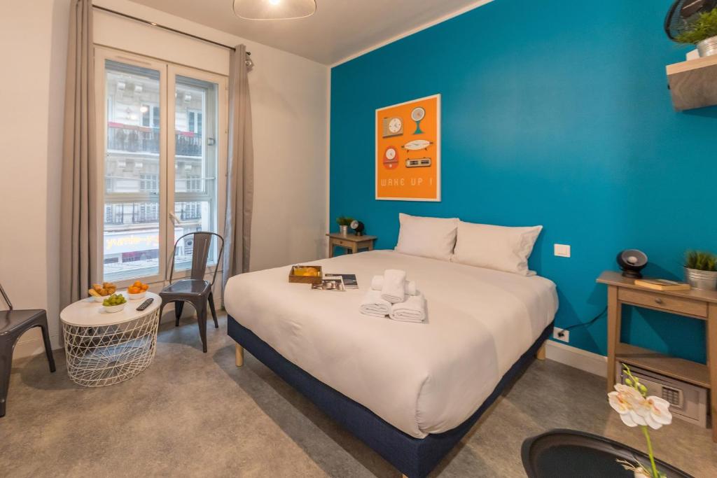 een slaapkamer met een groot bed en een blauwe muur bij Apartments WS Hôtel de Ville - Le Marais in Parijs