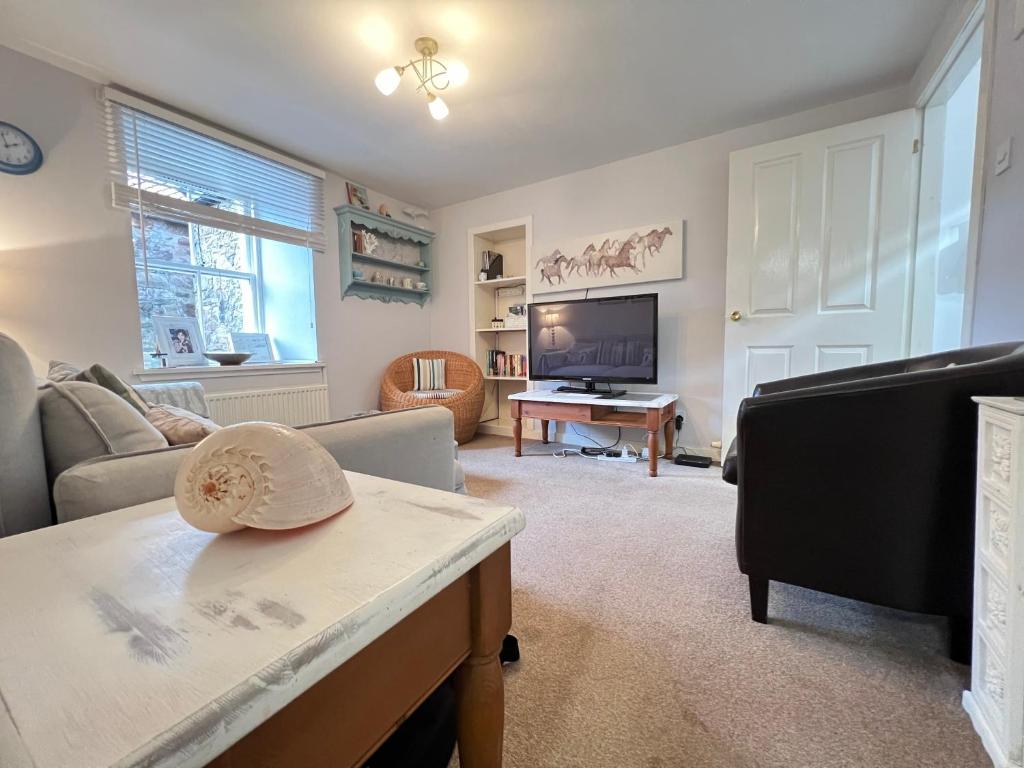 a living room with a couch and a tv at Quaint, cosy bolt hole in Cellardyke in Cellardyke