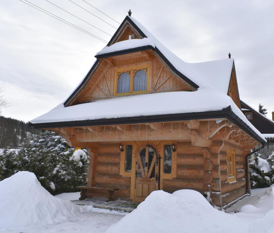 Cabaña de madera con nieve en el techo en Domek Góralski POD LASEM, en Witów