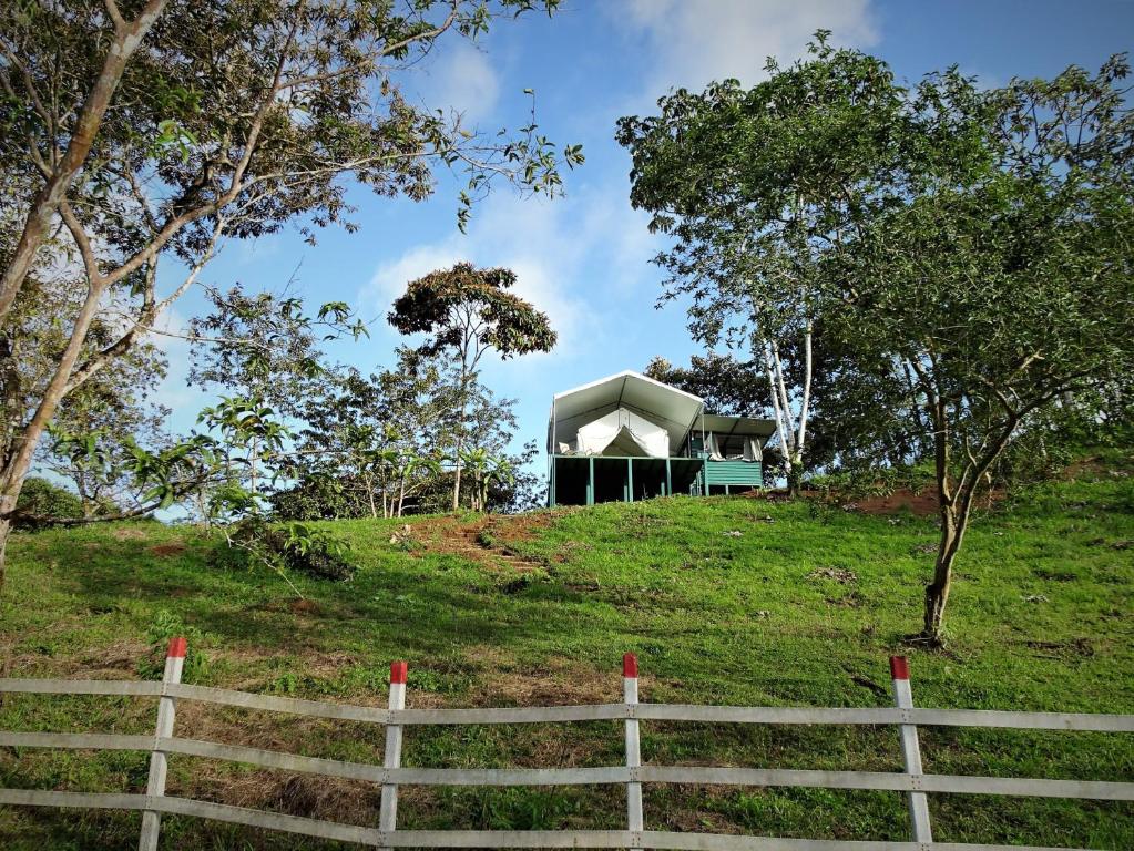 a house on top of a hill with a fence at Finca Tres Equis - Farm and Forest in Tres Equis