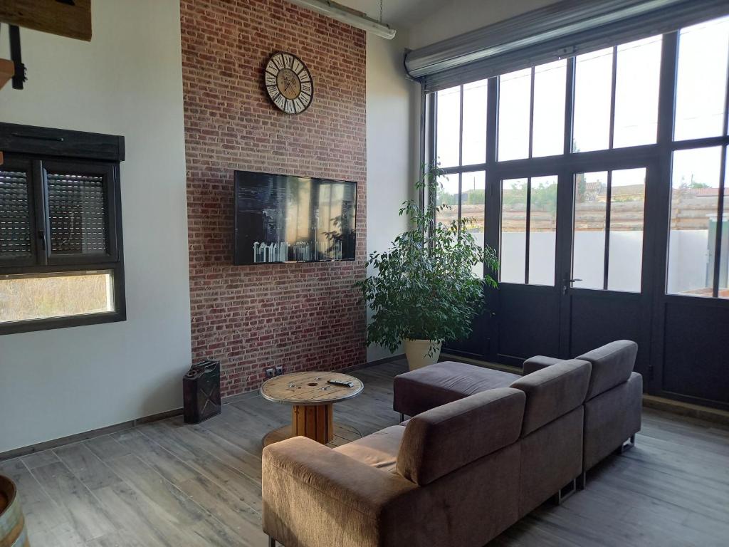 a living room with a couch and a clock on the wall at COSY-LOFT Industriel , jacuzzi , WIFI , 6 personnes max in Aigues-Vives