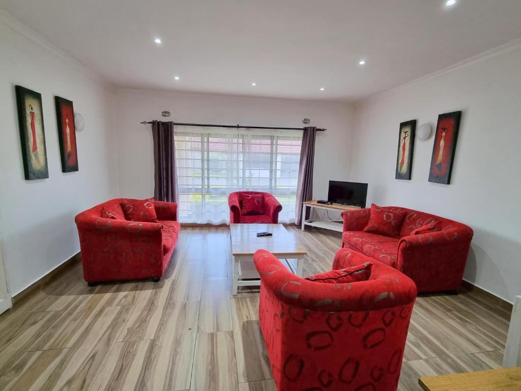 a living room with two red chairs and a table at Mwaiseni Maisonettes apartments in Ndola