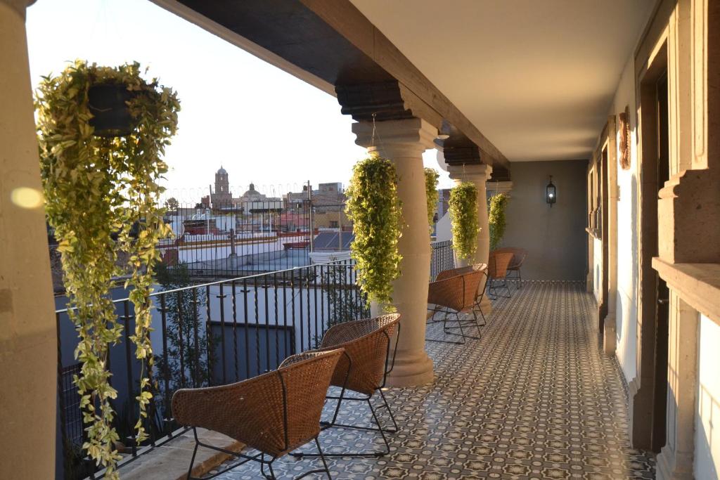 uma varanda com cadeiras e plantas num edifício em Hotel Boutique Casa Loreta em Querétaro