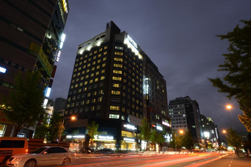 um edifício alto numa rua da cidade à noite em Dunsan Graytone Hotel em Daejeon