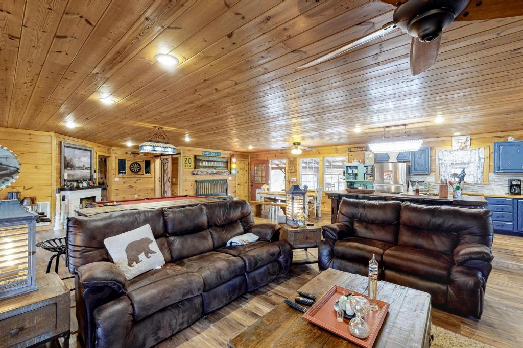 ein Wohnzimmer mit Ledersofas und einem Billardtisch in der Unterkunft Lucky Clover Cabin in Blairsville