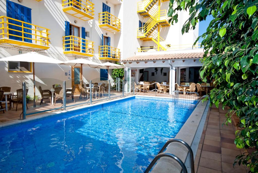 a swimming pool in a hotel with chairs and umbrellas at Hotel Bellavista in Cala Ratjada