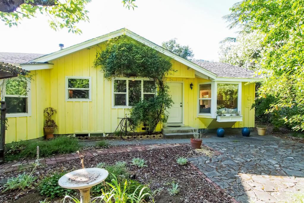 Cloverdale Creekside Retreat في كلوفرديل: منزل أصفر أمامه فناء حجري