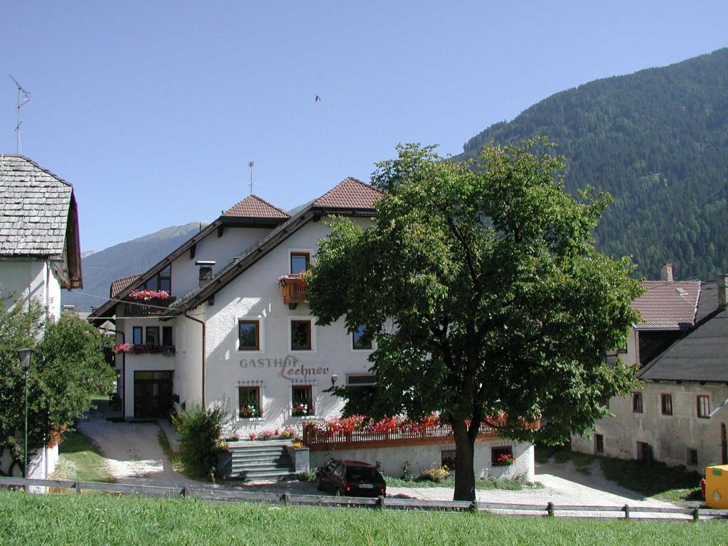 un gran edificio blanco con un árbol delante en Gasthof Lechner, en Rasun di Sopra