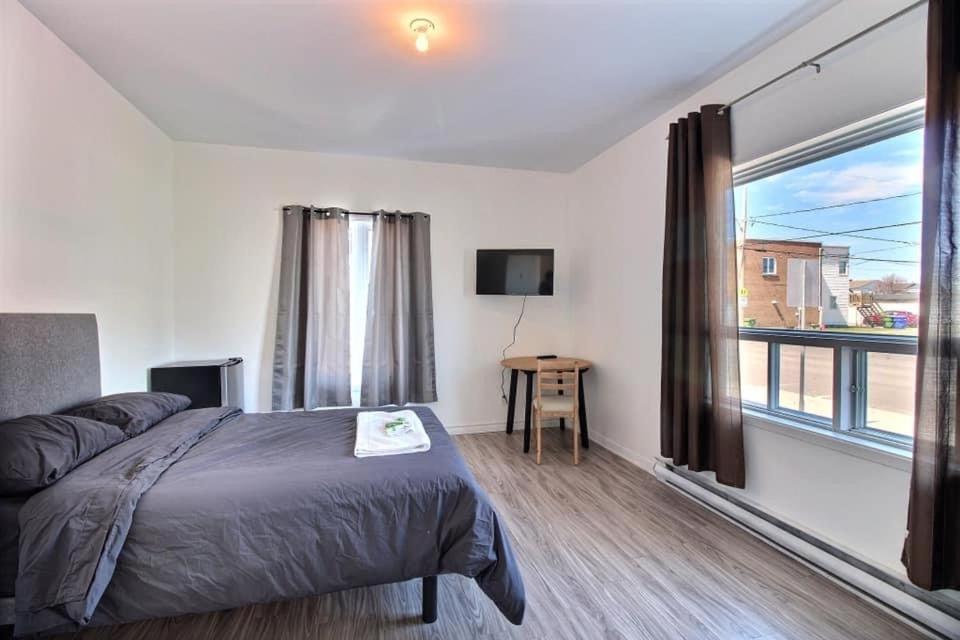 a bedroom with a bed and a large window at Chambres en ville La Tuque in La Tuque