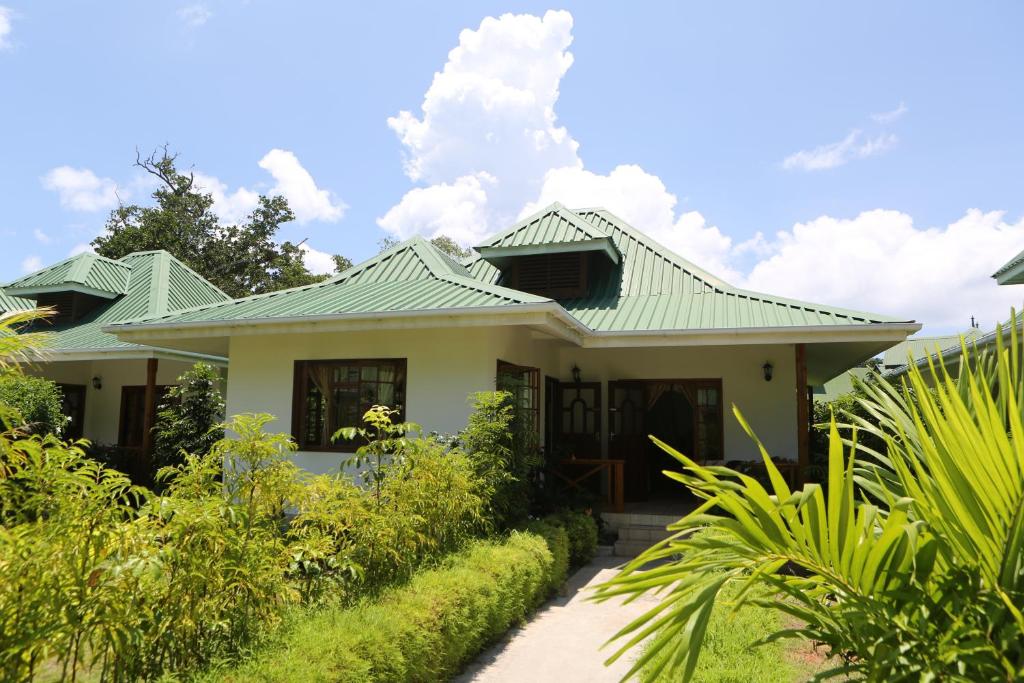 ein Haus mit grünem Dach in der Unterkunft Le Surmer Self Catering Chalets in La Digue