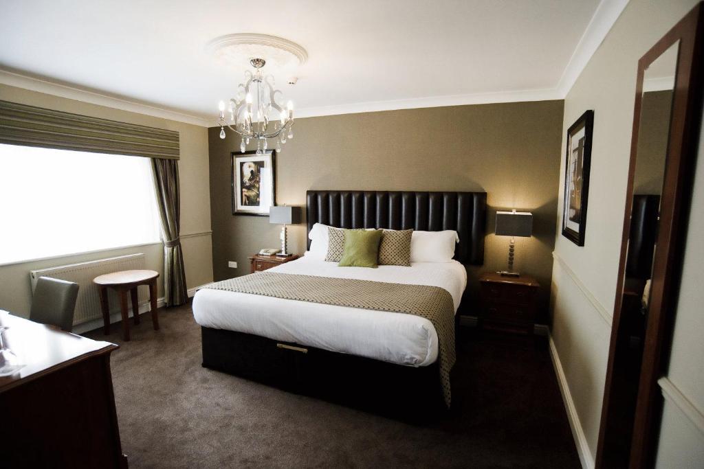 um quarto com uma cama grande e um lustre em The Ashbourne Hotel em North Killingholme