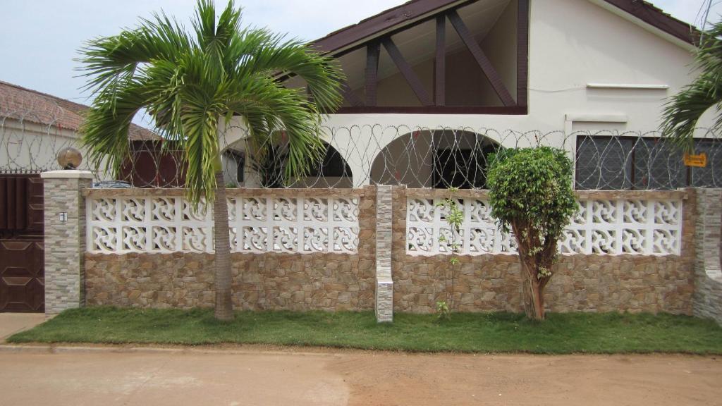 a fence with a palm tree in front of a house at Lashibi Villas in Teshi