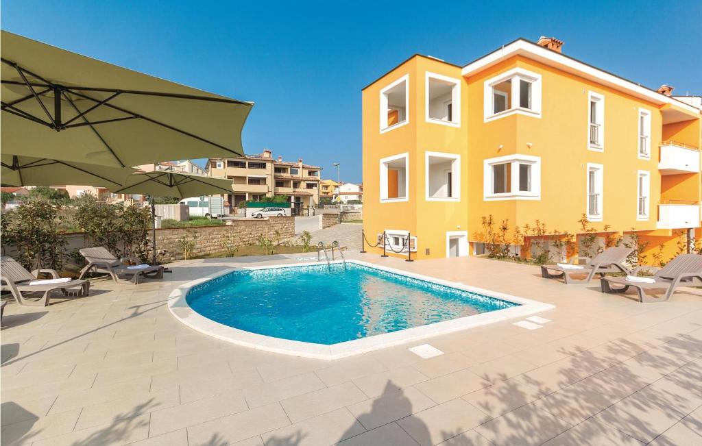 a swimming pool in front of a yellow building at Amazing Apartment In Premantura With Wifi in Premantura