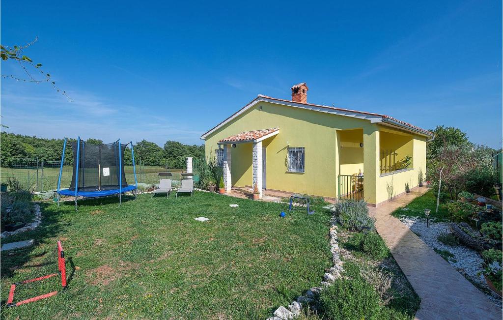 a small yellow house with a yard with a swing at Nice Home In Marcana With Wifi in Marčana