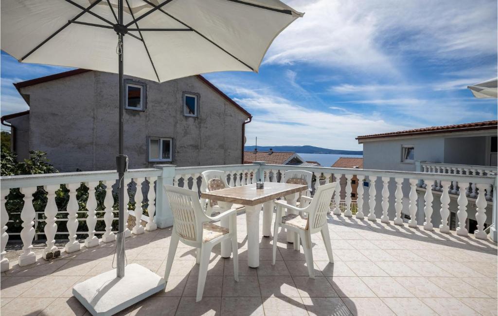 a white table and chairs on a balcony with an umbrella at Amazing Apartment In Crikvenica With Kitchenette in Crikvenica