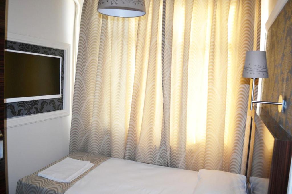 a bedroom with a bed and a tv and a curtain at Venus Hotel Taksim in Istanbul