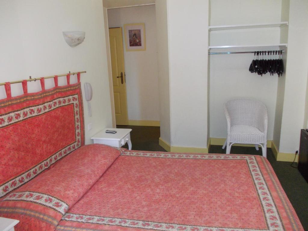 a bedroom with a red bed and a chair at Hotel Marcellin in Beaulieu-sur-Mer