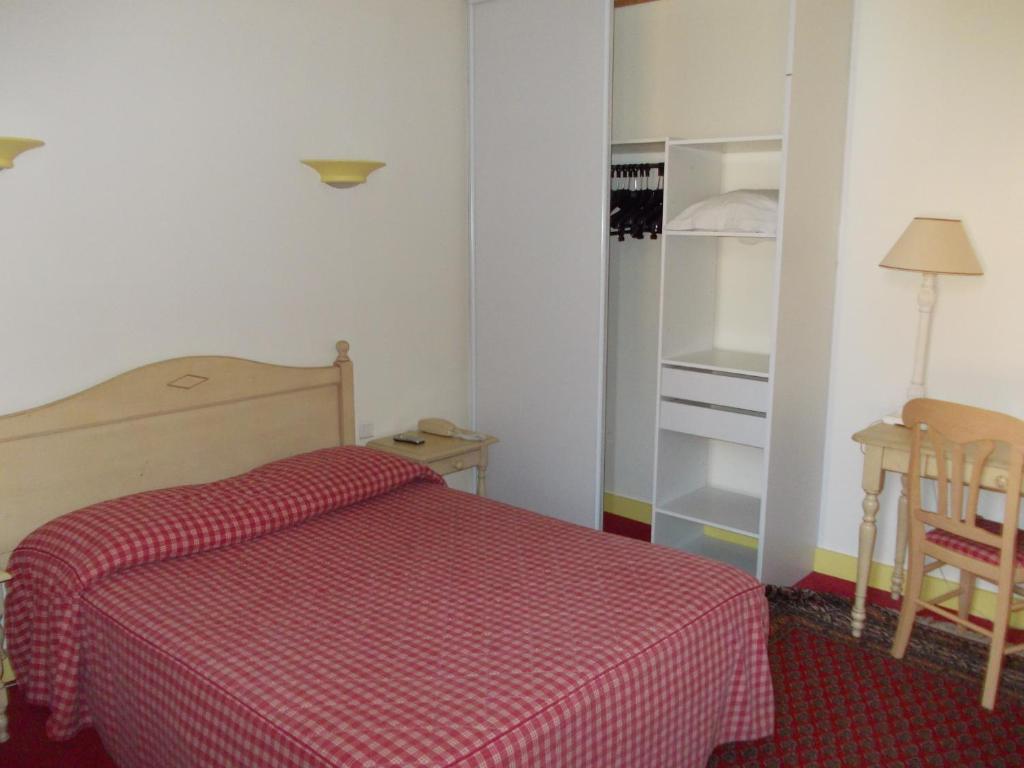 a bedroom with a bed with a red checkered blanket at Hotel Marcellin in Beaulieu-sur-Mer