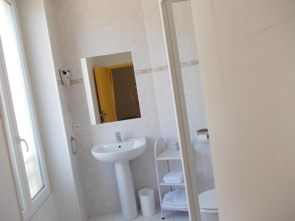 a white bathroom with a sink and a mirror at Hotel Marcellin in Beaulieu-sur-Mer