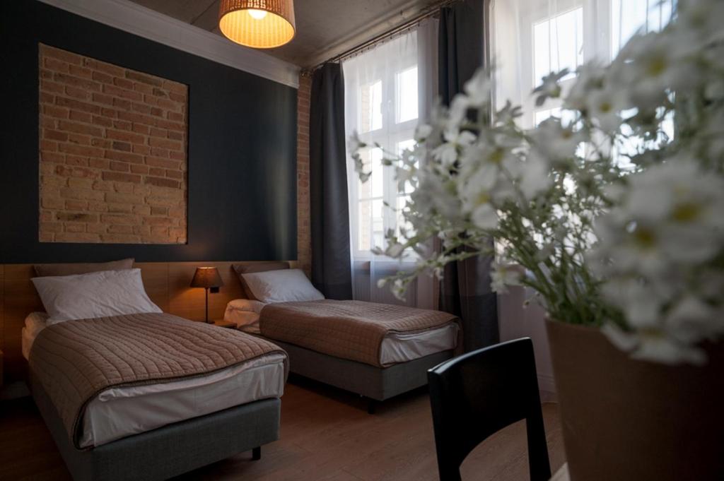 a bedroom with two beds and a chair and flowers at Qbatura Cafe & Hotel in Ciechanów