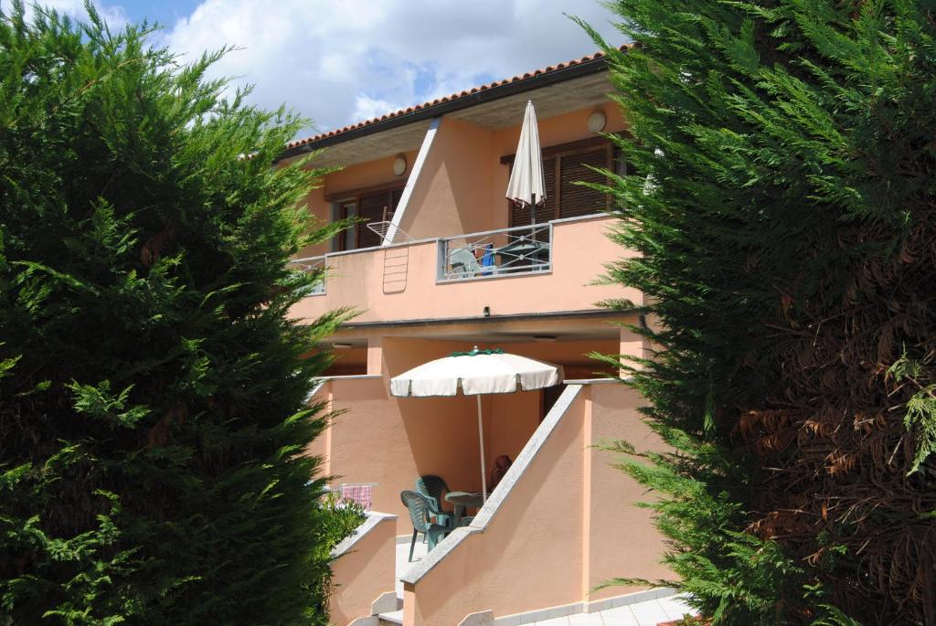 a house with a balcony with an umbrella at Residence Dolores in Marina di Campo