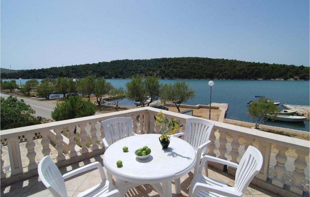 a table and chairs on a balcony with a view of the water at Cozy Apartment In Jadrtovac With House Sea View in Jadrtovac