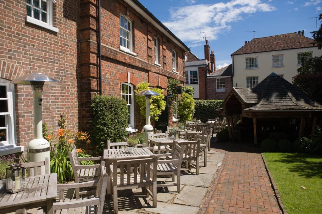 a row of wooden tables and chairs in front of a building at Hotel du Vin Winchester in Winchester