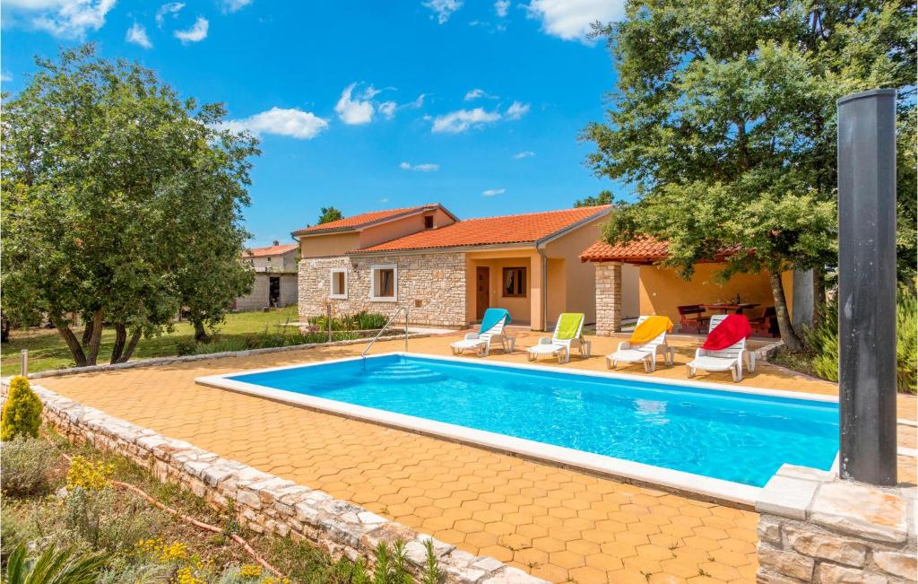 een zwembad in een tuin met stoelen en een huis bij 3 Bedroom Beautiful Home In Skicini in Juršići