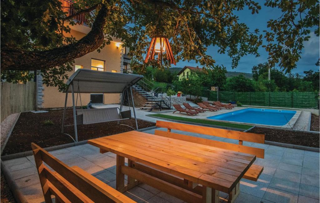 a wooden bench sitting next to a swimming pool at Stunning Home In Vinjani Donji With 5 Bedrooms, Wifi And Outdoor Swimming Pool in Majići