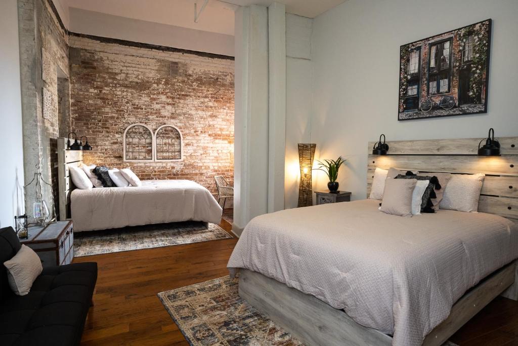 a bedroom with two beds and a brick wall at French Quarter Q in New Orleans