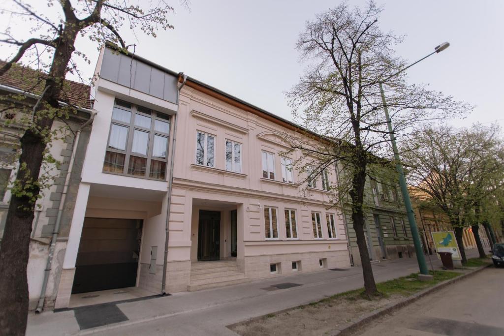 un gran edificio blanco al lado de una calle en Hotel Ankavi en Szeged