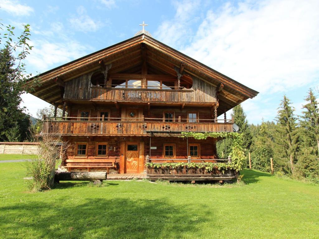 un grand bâtiment en bois dans un champ d'herbe dans l'établissement Farmhouse in Hopfgarten in Brixental with garden, à Hopfgarten im Brixental