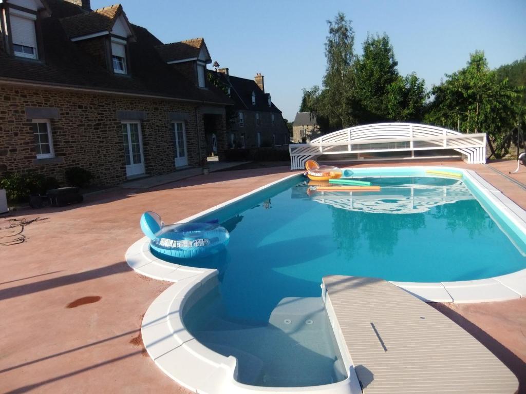 einen Pool mit aufblasbarem Poolspielzeug in einem Hof in der Unterkunft Gîtes de L'Aumondière in Condé-sur-Noireau
